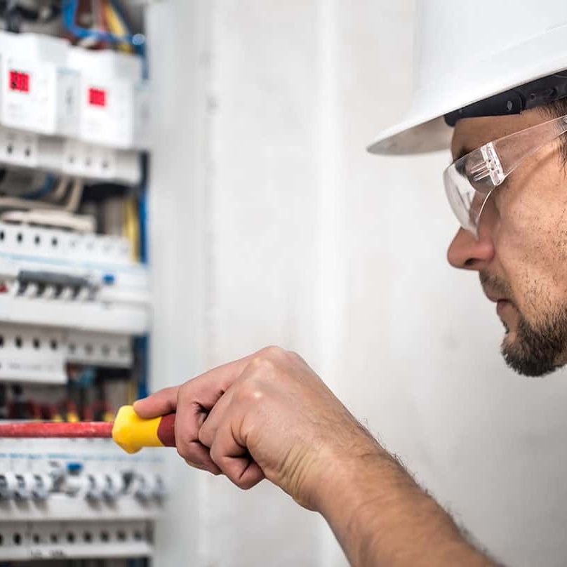 man-electrical-technician-working-switchboard-with-fuses-installation-connection-electrical-equipment-close-up